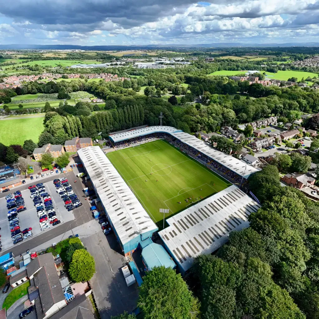 An aerial view of Gigg Lane, Bury's football ground, with car parks, trees and streets of houses around it