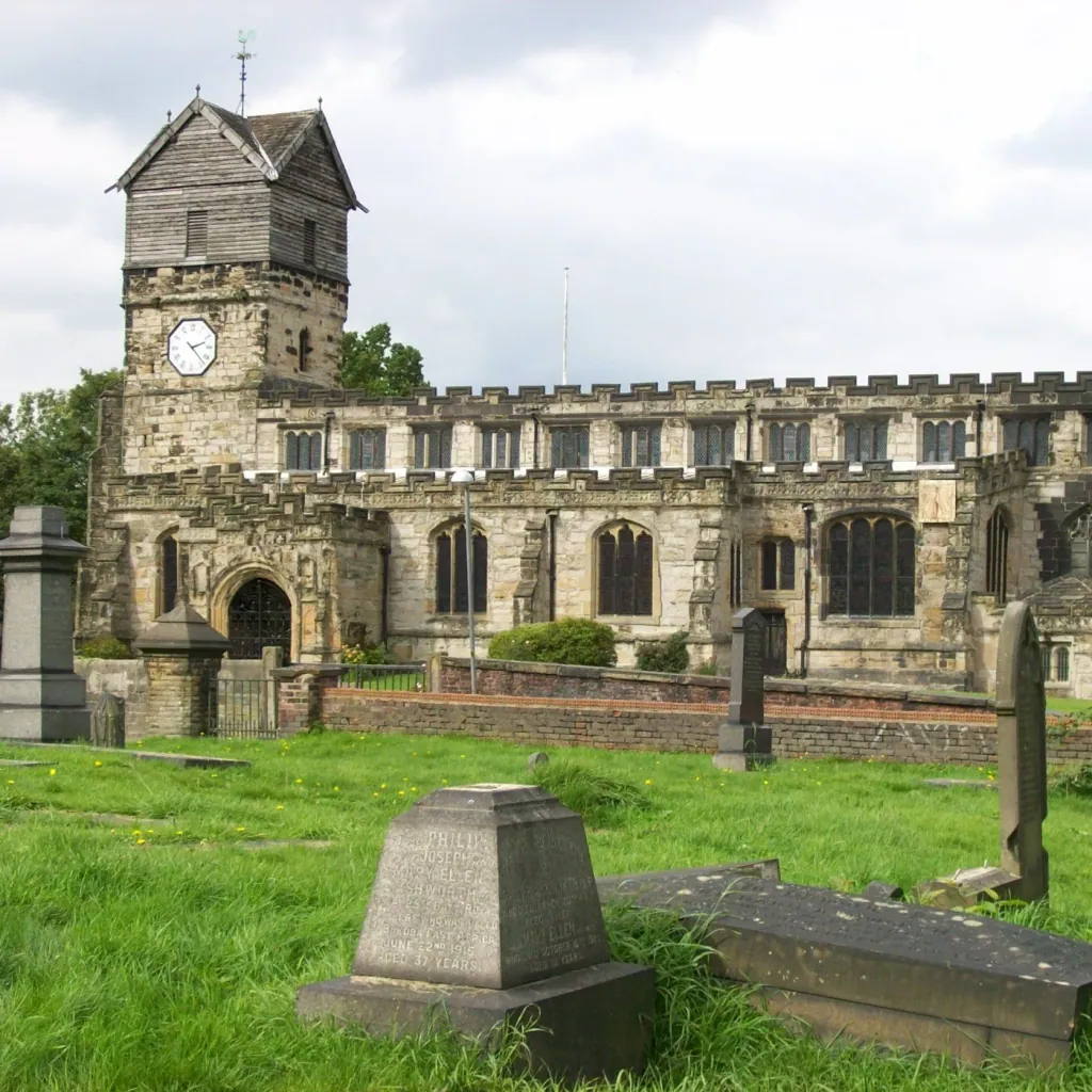 St Leonard's Church in Middleton, its timber belfry above the stone tower, behind gravestones in the churchyard